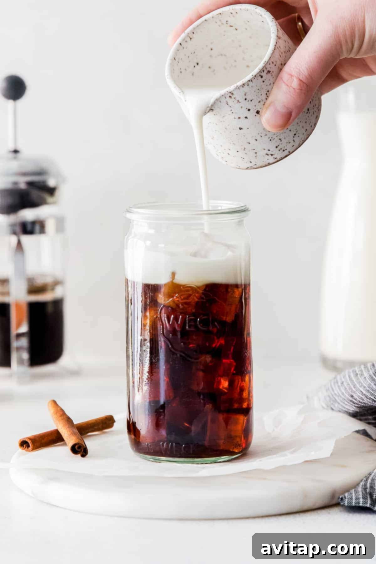 Adding Oat Milk to Coffee Pouring creamy oat milk into a coffee glass.