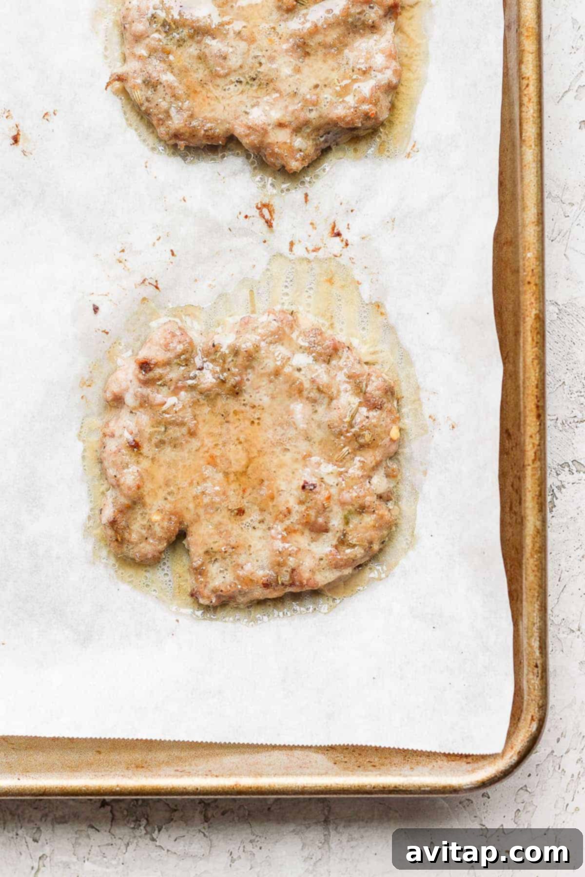 Several cooked breakfast sausage patties arranged on a baking sheet, showcasing their golden-brown color.