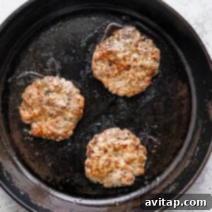 Sizzling homemade maple breakfast sausage patties cooking in a skillet, showcasing their delicious golden-brown crust.