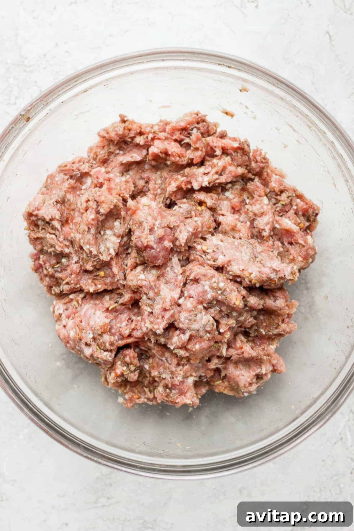 A large bowl holding the seasoned ground pork and turkey mixture, perfectly combined and ready for shaping into patties.