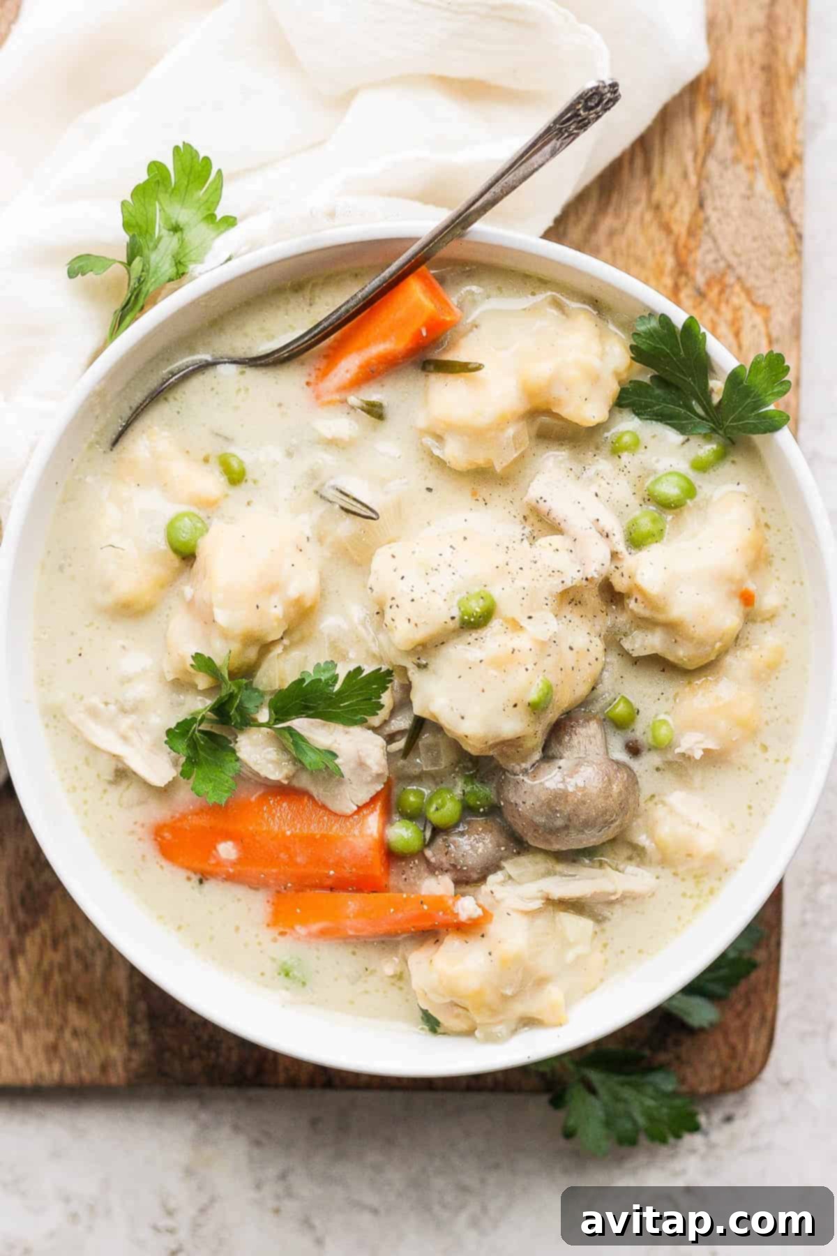 Hearty slow cooker chicken and dumplings in a bowl, garnished with fresh parsley.