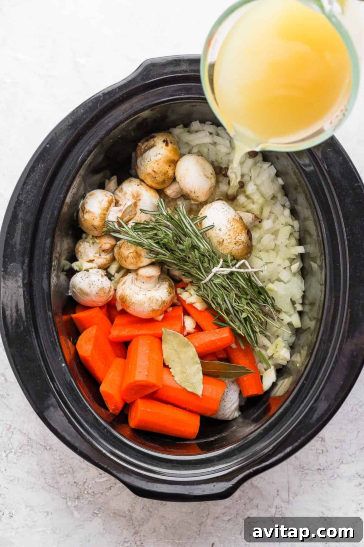 Assorted fresh ingredients for slow cooker chicken and dumplings arranged inside a slow cooker before cooking.