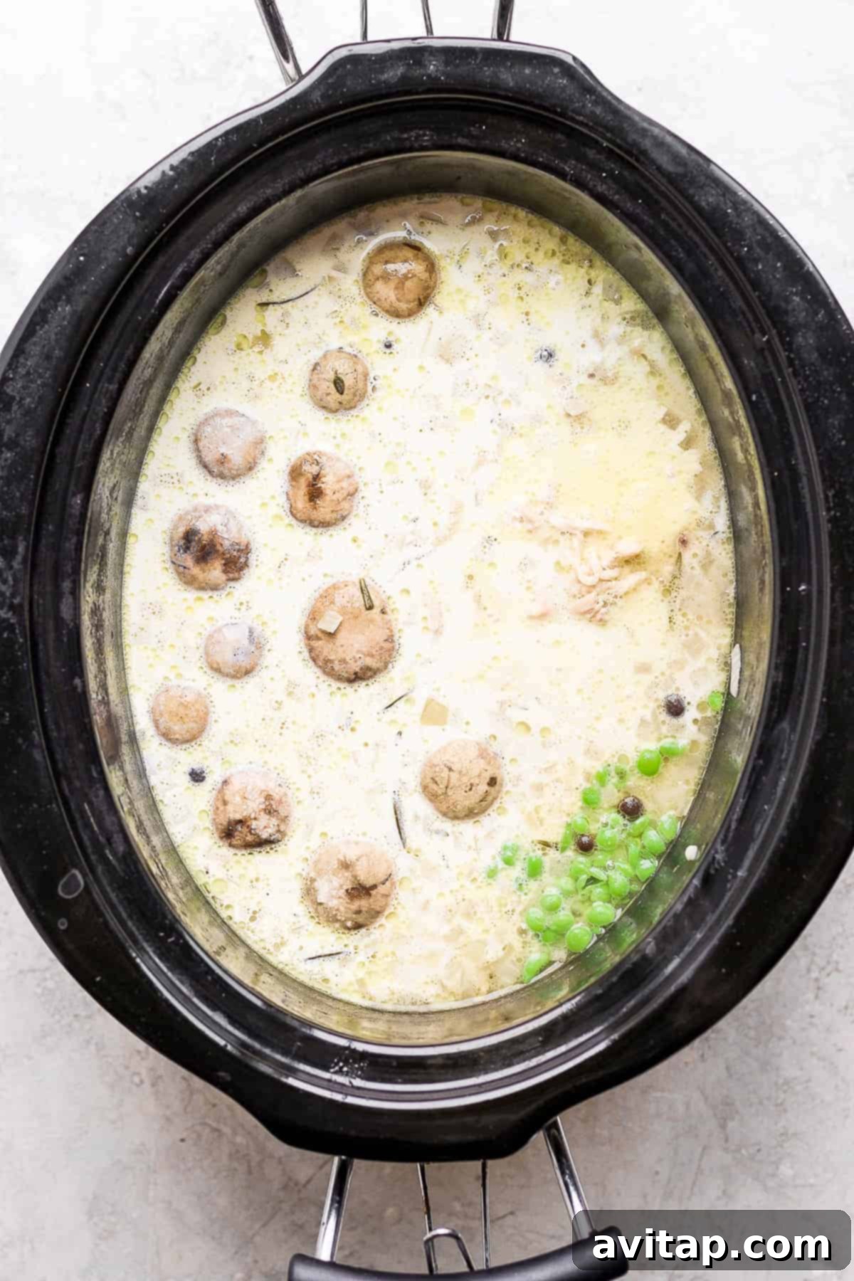 Close-up of bubbling slow cooker chicken and dumplings, showing the creamy broth and tender dumplings.