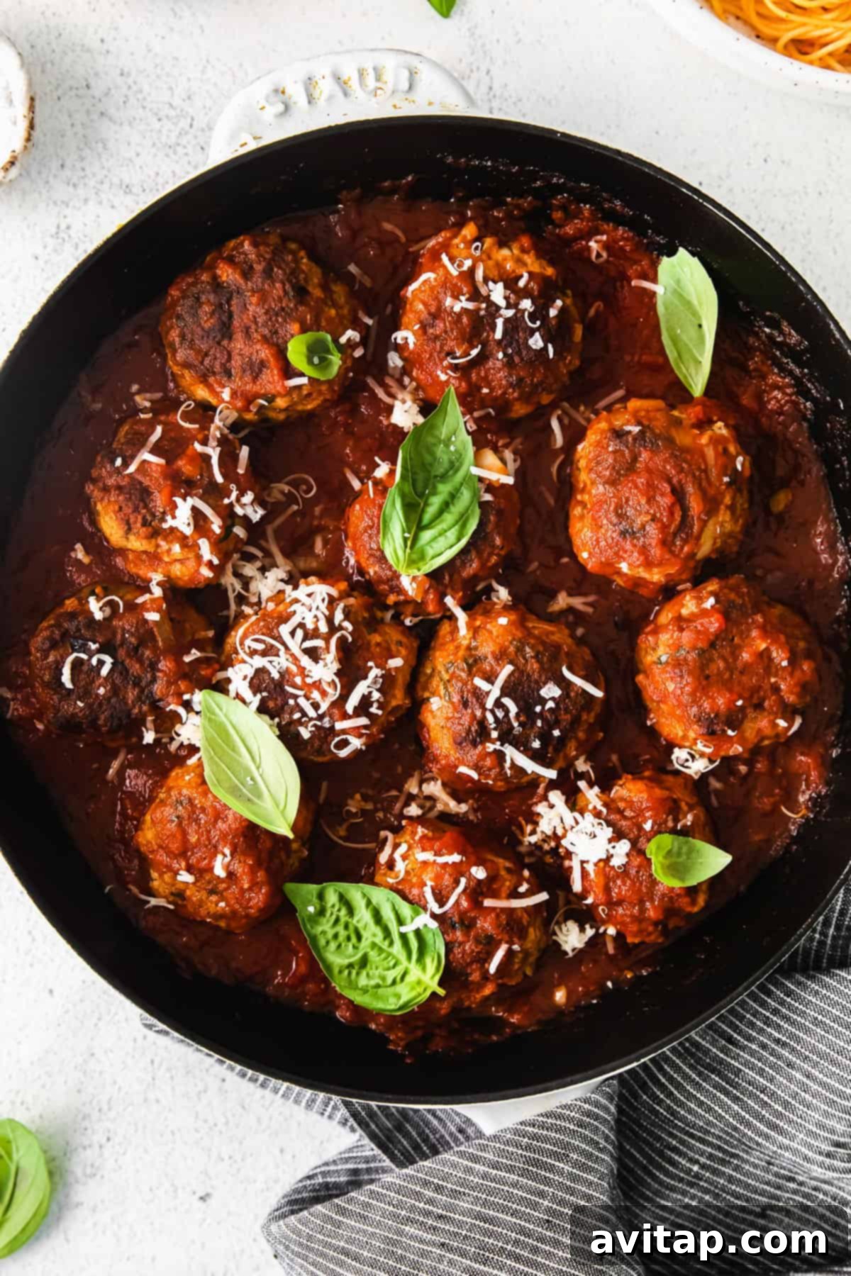 A batch of perfectly formed, uncooked ground turkey meatballs on a clean surface, ready for cooking