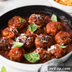 Turkey meatballs fully submerged and simmering in a rich tomato marinara sauce in a skillet