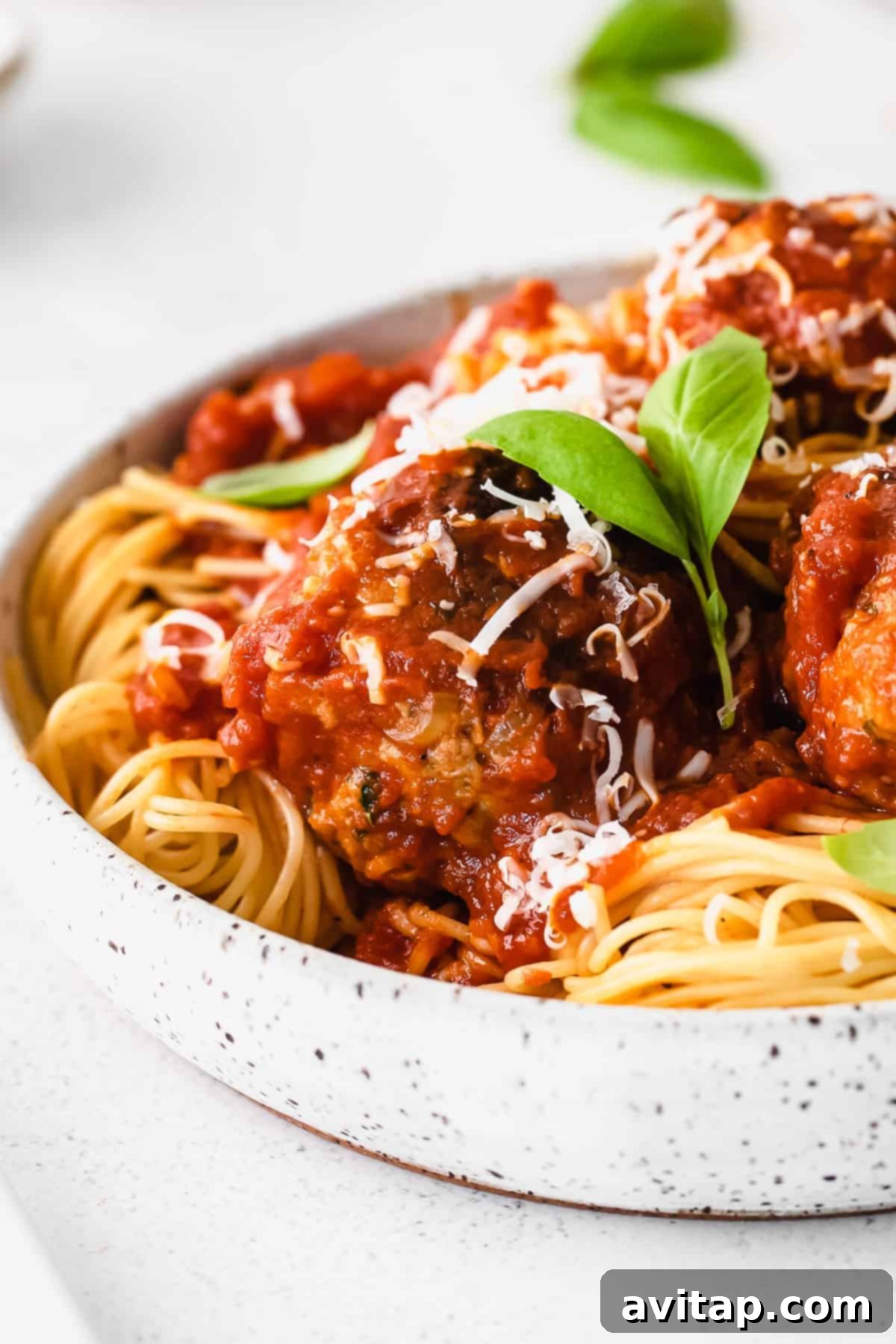 A rustic basket filled with assorted freshly baked bread rolls, perfect for soaking up marinara sauce with meatballs