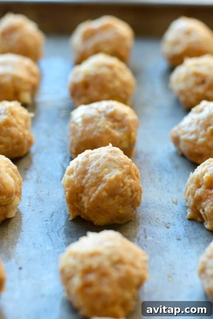 Baked chicken meatballs on a baking sheet, ready for sauce.
