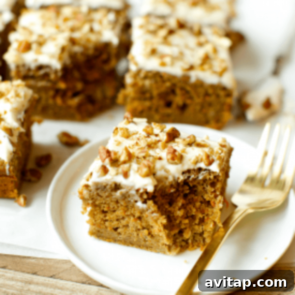 A slice of carrot cake on a plate with a gold fork.