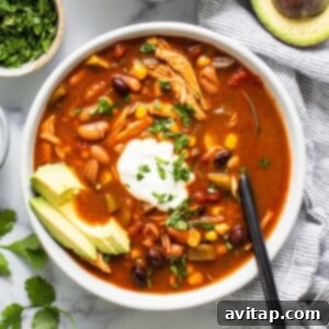 A bowl of chicken enchilada soup with avocado and sour cream, ready to be served and enjoyed.