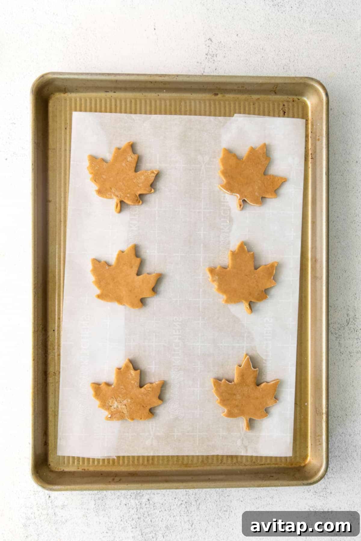 maple sugar cookie cut-outs arranged neatly on a parchment-lined baking sheet, ready for freezing
