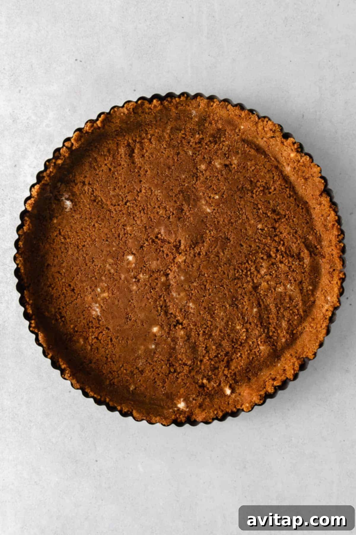 Golden Apple Tart 6 A baked golden-brown gingersnap crust cooling in a 9-inch tart pan, ready for the apple filling.