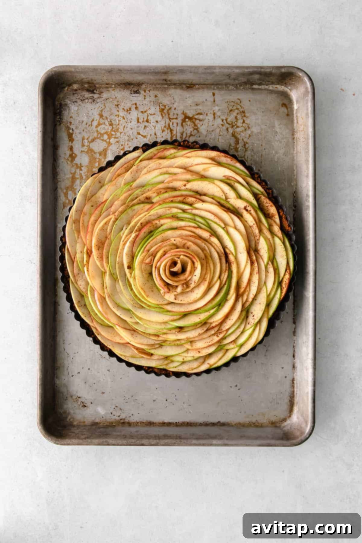 Golden Apple Tart 7 An unbaked apple tart with a meticulously arranged apple rose pattern, showcasing the spiced apple slices before baking.