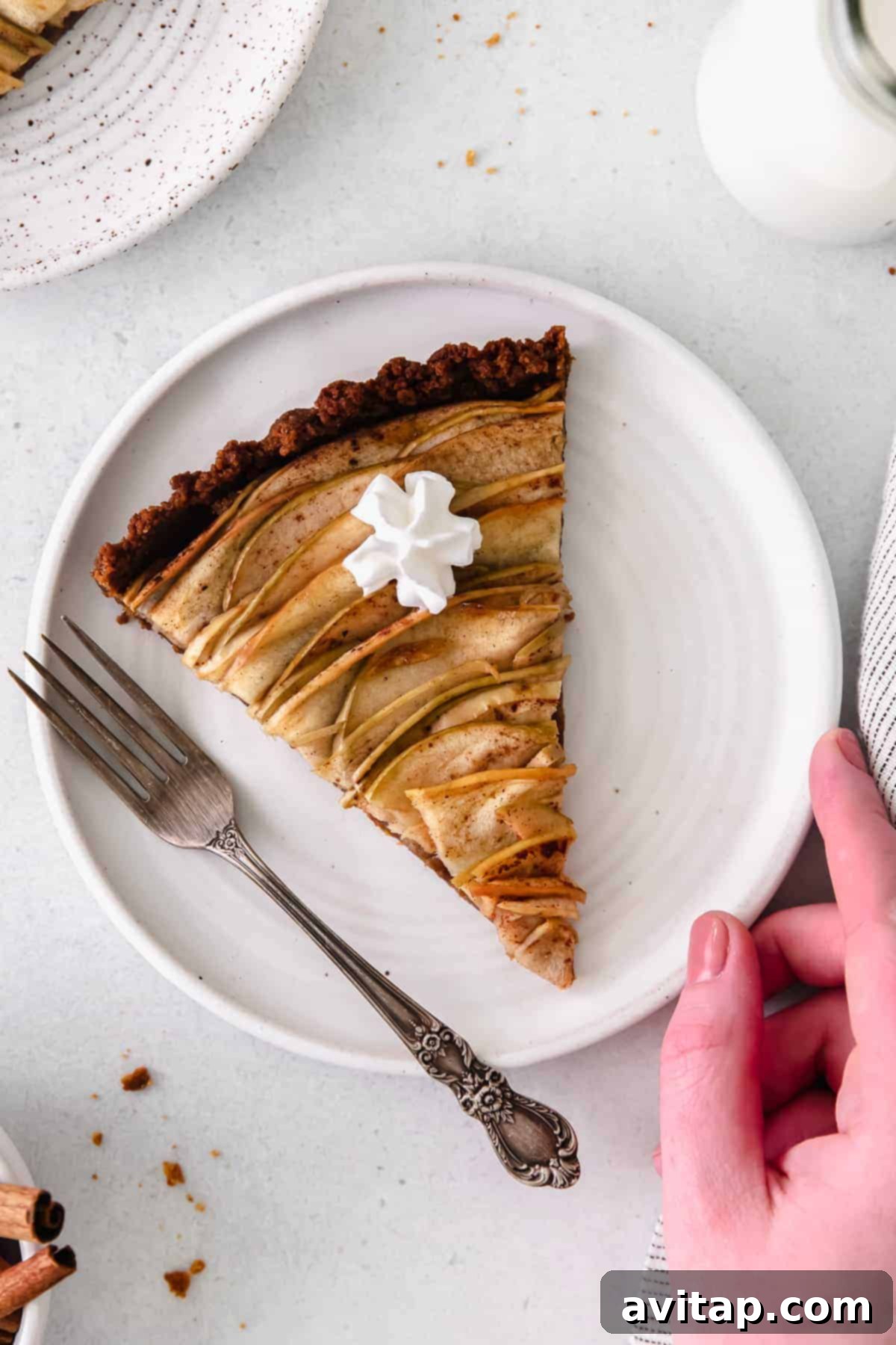 Golden Apple Tart 8 A whole baked apple rose tart on a white plate, ready to be served, highlighting its elegant presentation.