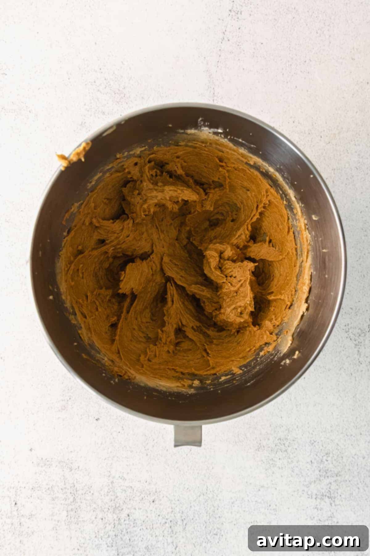 Close-up of butter and sugar being creamed together in a stand mixer, creating a light and fluffy mixture.
