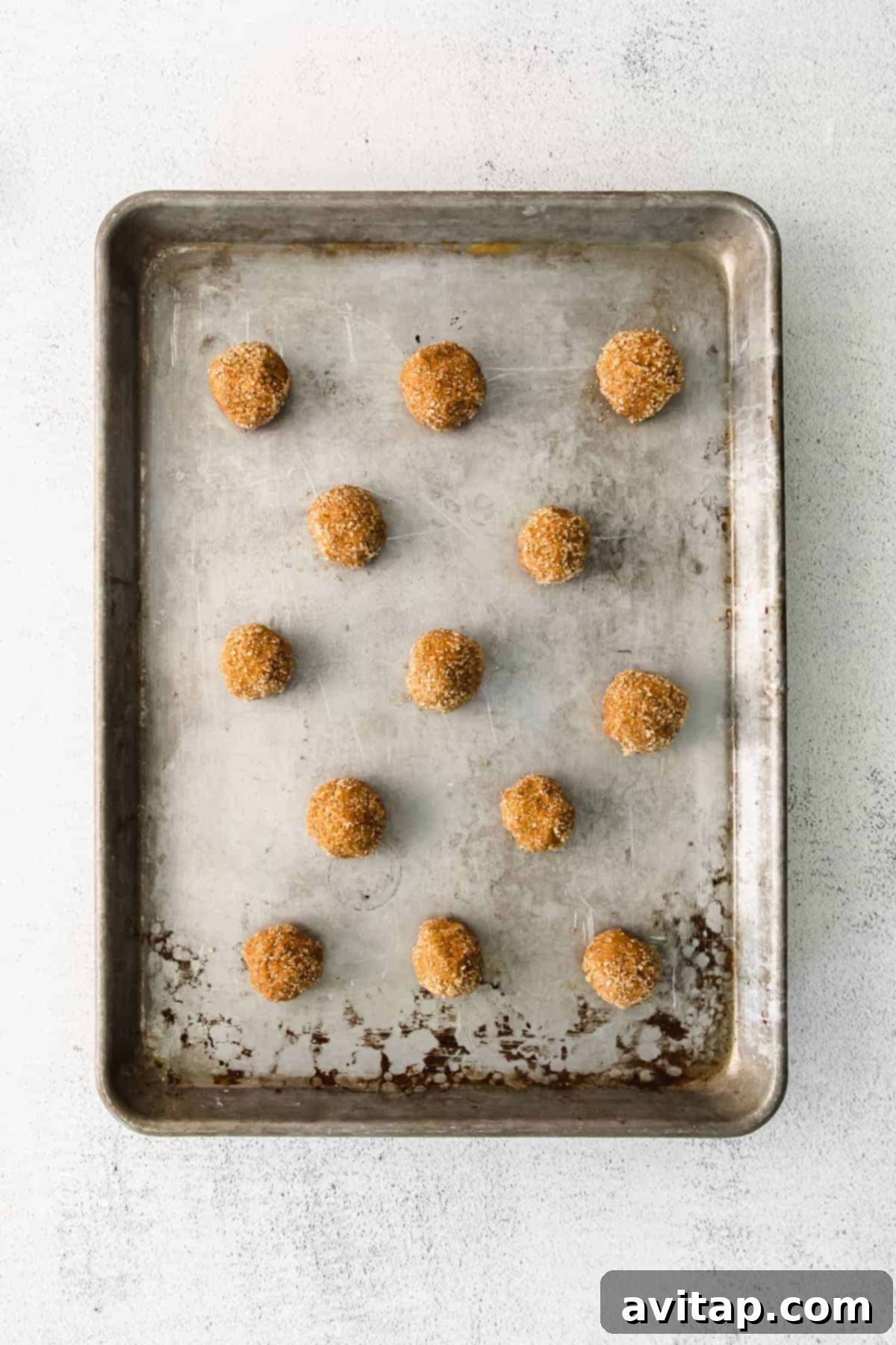 Ginger whoopie pie cookie dough balls rolled in sparkling turbinado sugar, perfectly arranged on a baking sheet, ready for the oven.