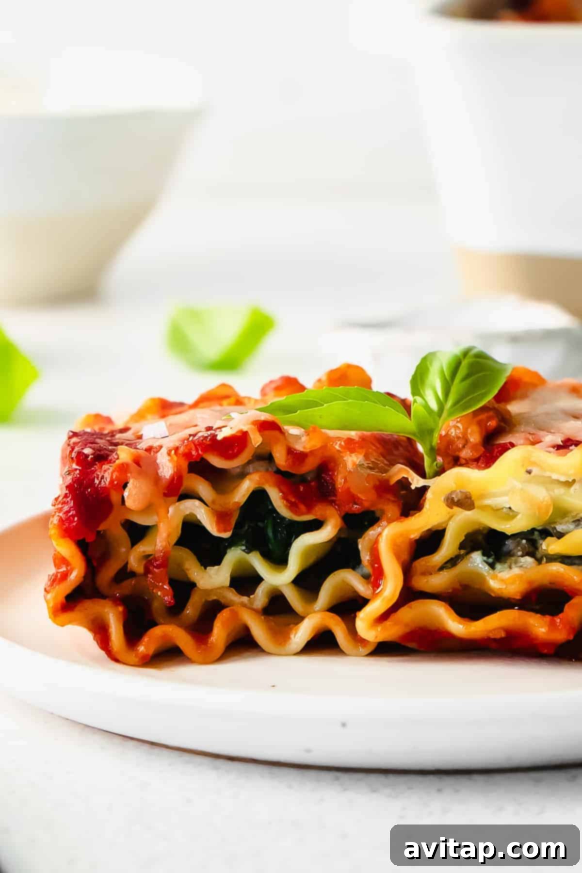 Perfectly baked golden-brown lasagna roll ups on a white plate, garnished with fresh herbs, ready to be served and enjoyed. This close-up highlights the rich textures and appealing presentation.