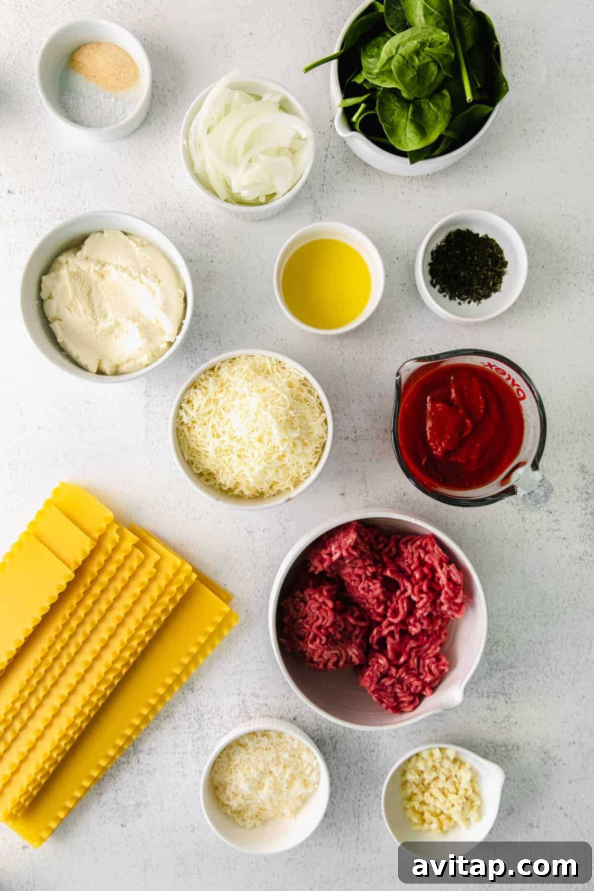 An inviting display of fresh and vibrant ingredients for homemade lasagna roll ups, including ground beef, spinach, ricotta, mozzarella, and marinara, artfully arranged on a clean kitchen counter, ready for preparation.