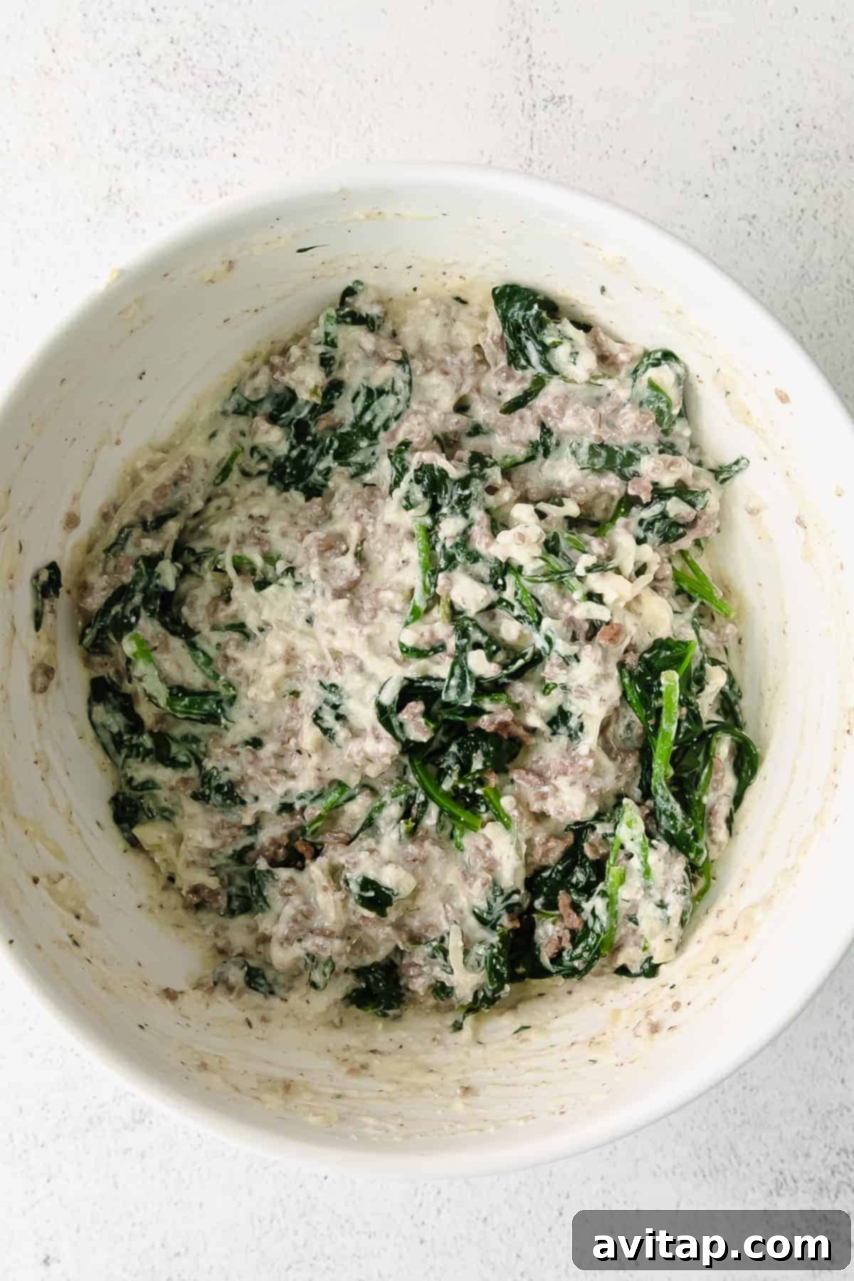 A large, inviting bowl filled with the creamy, savory, and vibrant green lasagna roll up filling, showcasing its rich texture and delicious ingredients, ready for assembly into noodles.
