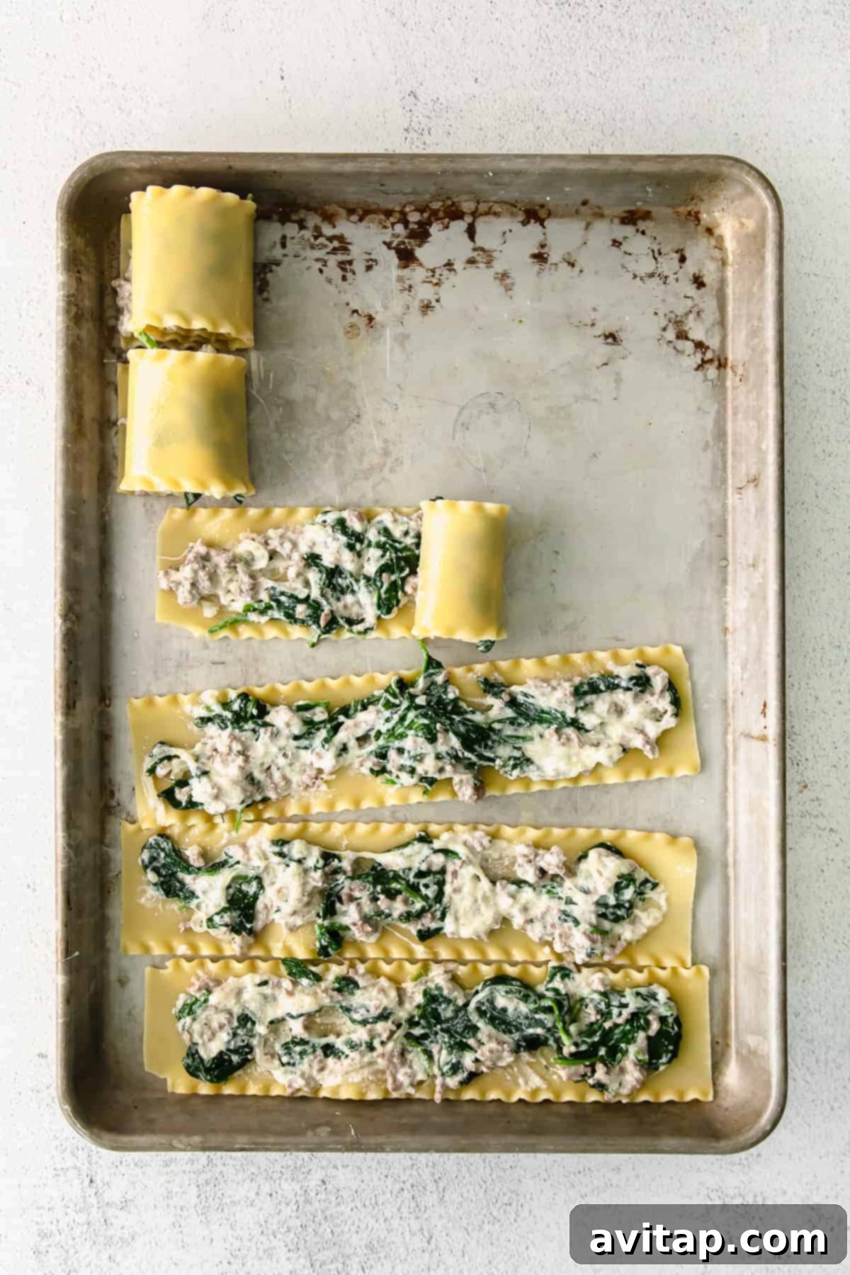 Cooked lasagna noodles laid flat in an organized manner on a baking sheet, glistening with a light drizzle of olive oil, perfectly prepared and ready for the next step of filling and rolling.