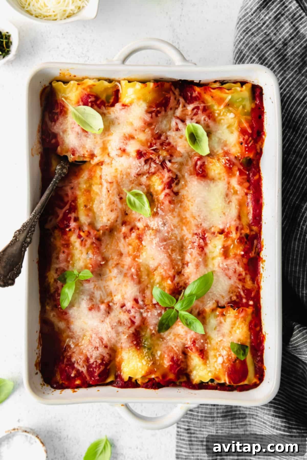 A close-up view of perfectly baked lasagna roll ups in a casserole dish, topped with bubbling melted cheese and garnished with fresh basil, showcasing their delicious appeal and ready-to-eat perfection.