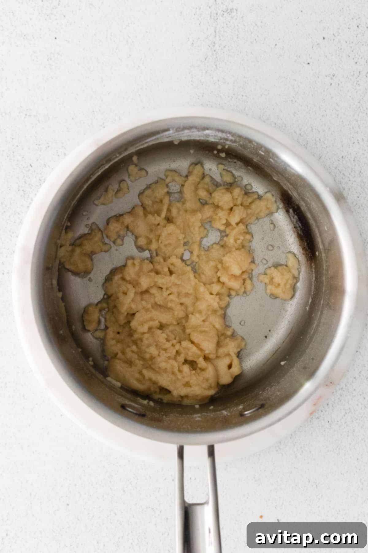 Melted butter and flour forming a roux in a small saucepan, the starting point for our homemade cheese sauce for cheesy potato casserole.