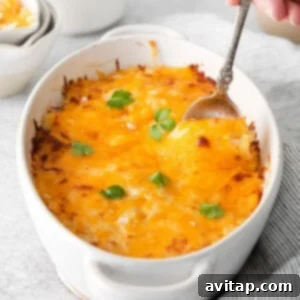 A top-down view of the Cheesy Potato Casserole, showcasing its golden-brown crust and a hint of the bubbling cheese underneath, presented in a white baking dish.