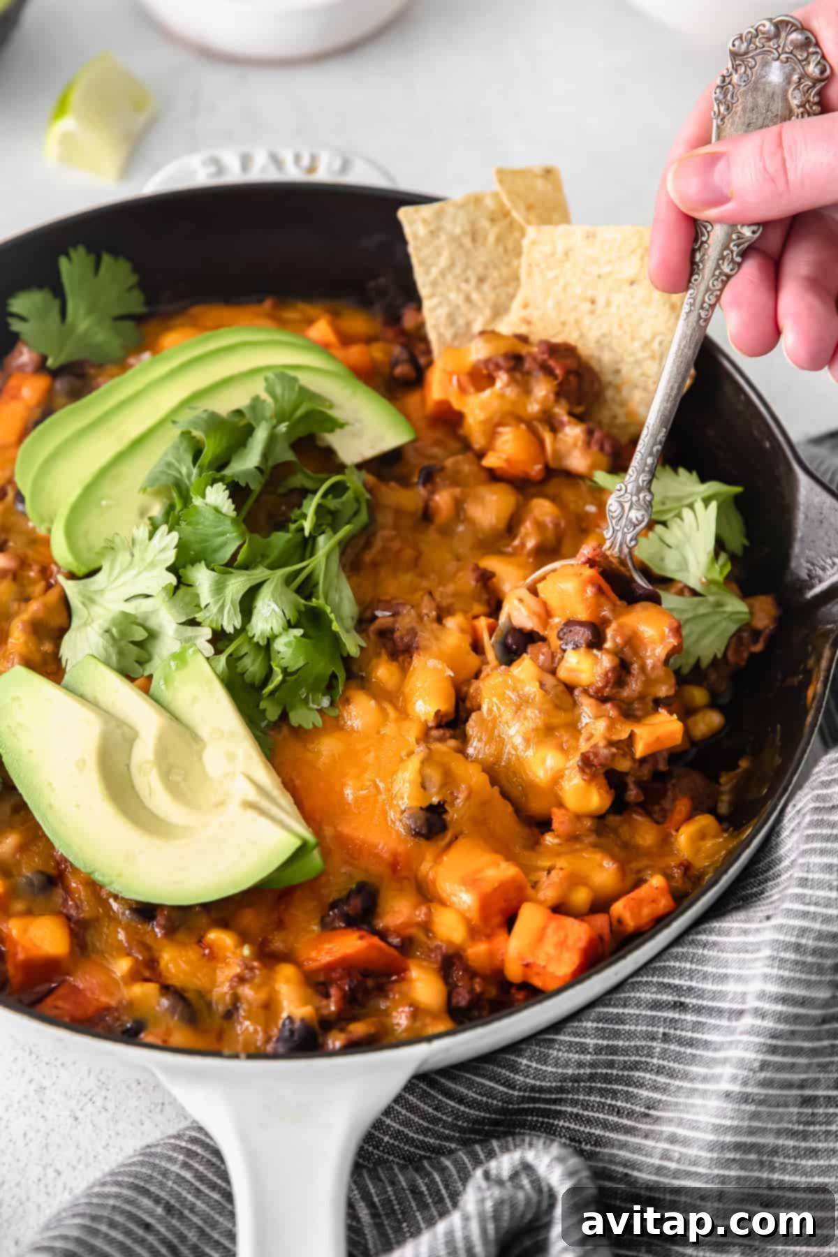 A close-up shot of the savory turkey sweet potato enchilada skillet served on a spoon, highlighting its rich texture and colorful ingredients.