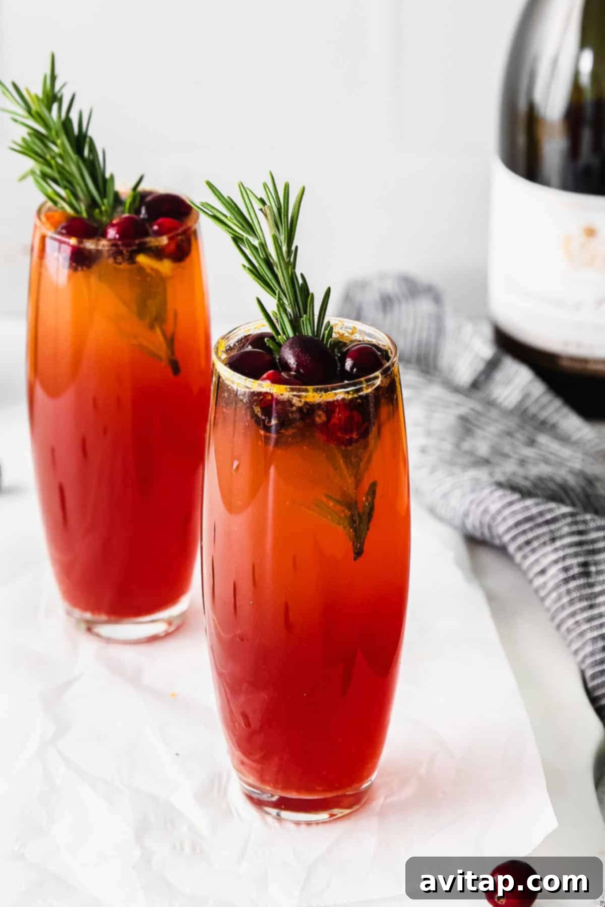 Vibrant Cranberry Mimosa in a flute glass, garnished with fresh cranberries and rosemary.