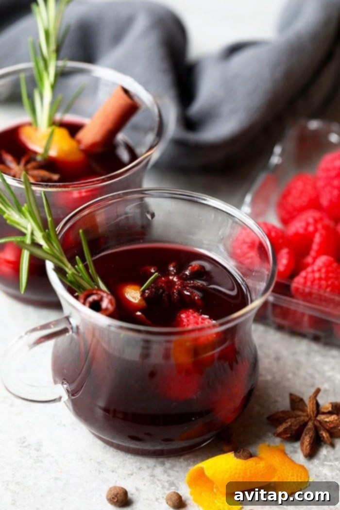 Steaming mulled wine in a glass mug with orange slices and star anise.