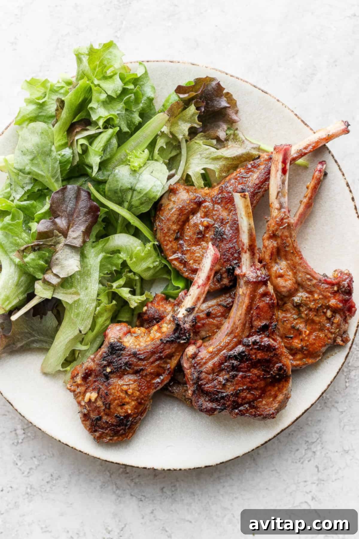 pan seared lamb chops on a plate next to a salad