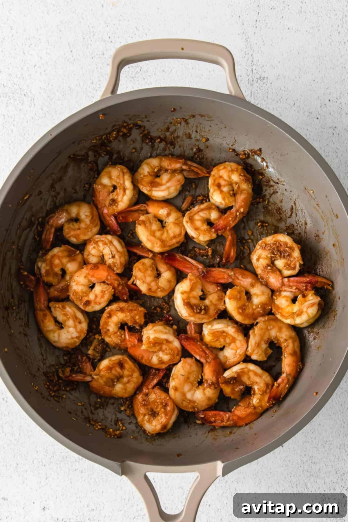 Garlic Butter Shrimp 6 Cooked shrimp plated with fresh herbs and sesame seeds.