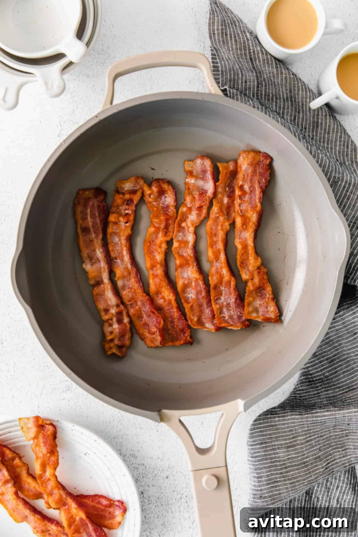 Bacon strips sizzling in a hot frying pan on the stovetop