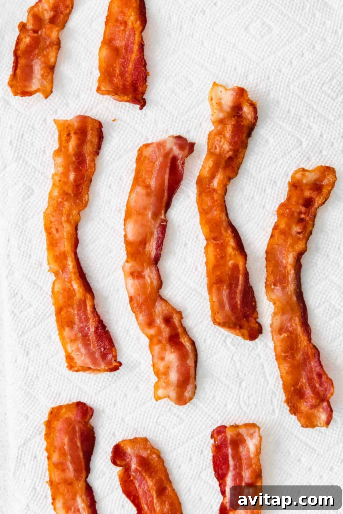 Crispy bacon resting on a paper towel-lined plate to drain excess grease