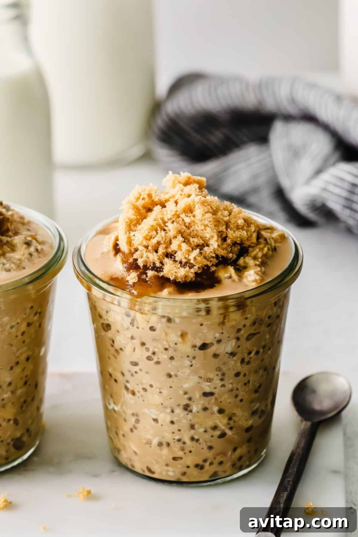 Ready-to-eat coffee overnight oats in a mason jar, garnished with a sprinkle of brown sugar and a small spoon.