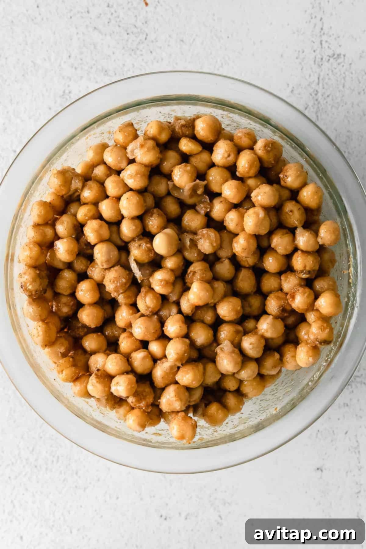 Chickpeas marinating in a bowl with spices and ghee, infusing them with deep flavor.