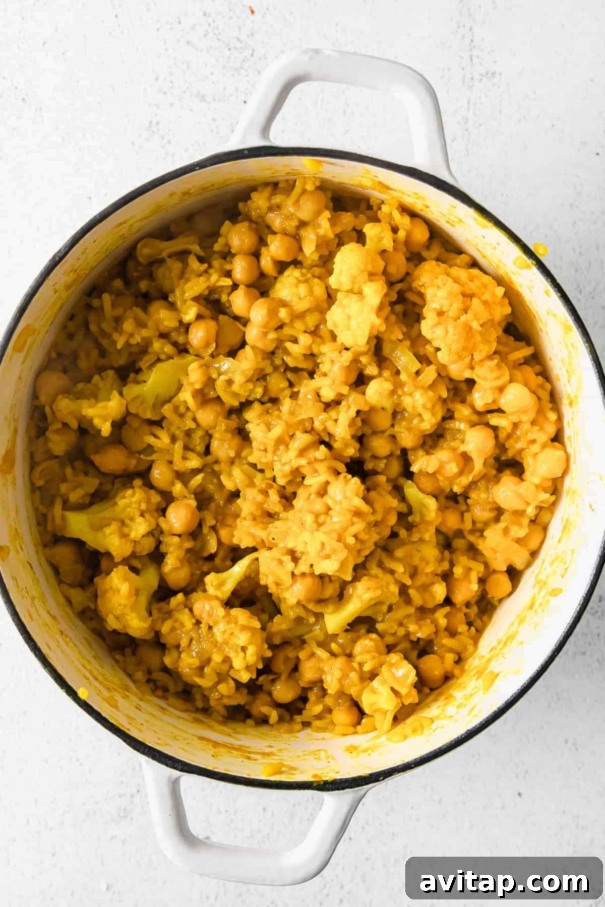A close-up of creamy, perfectly cooked yellow rice with tender chickpeas and cauliflower, ready to be served.
