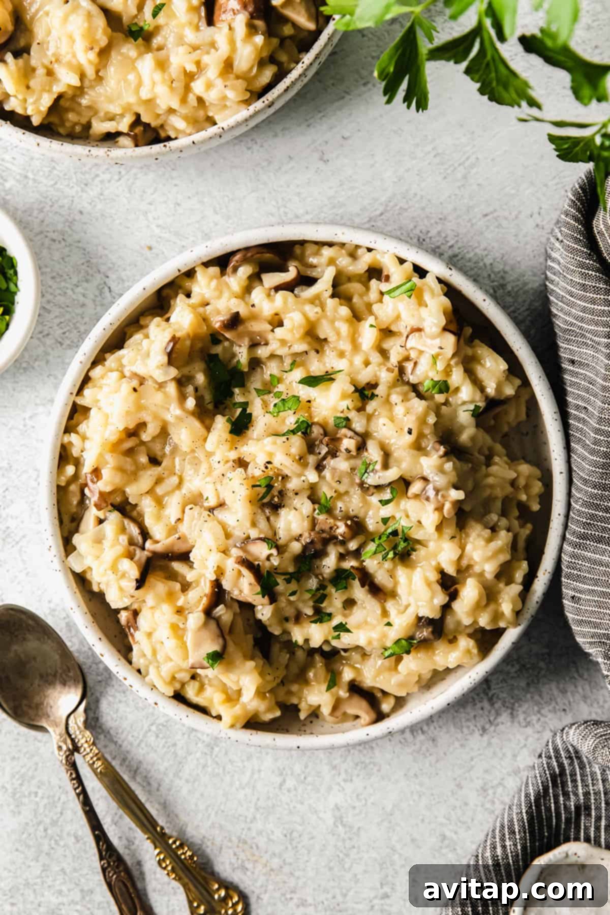 Effortless Creamy Mushroom Risotto 2 Instant Pot mushroom risotto in a bowl, garnished with fresh herbs and a sprinkle of cheese.
