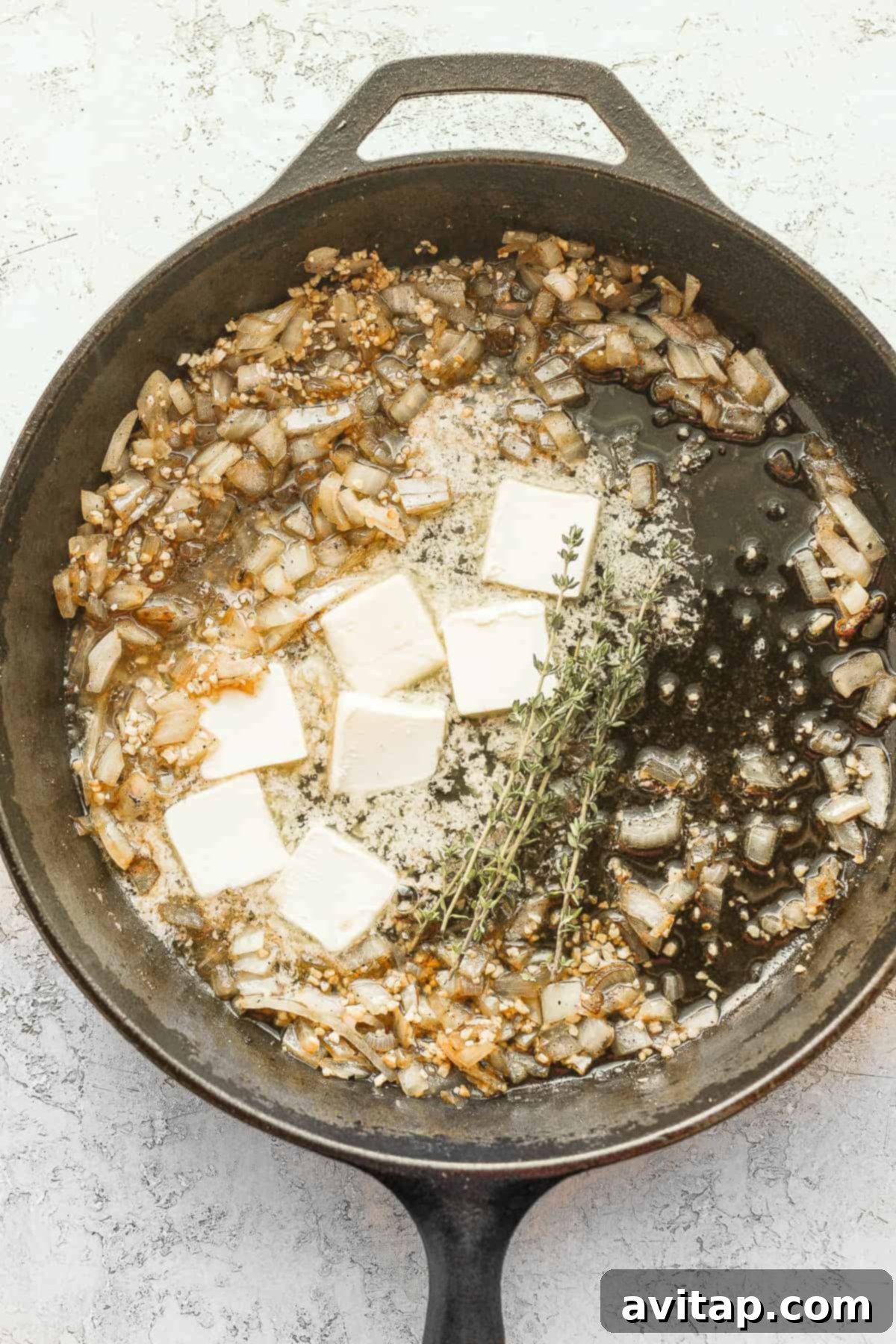 Melted butter, minced onion, and garlic sautéing in a cast iron skillet, creating an aromatic base.