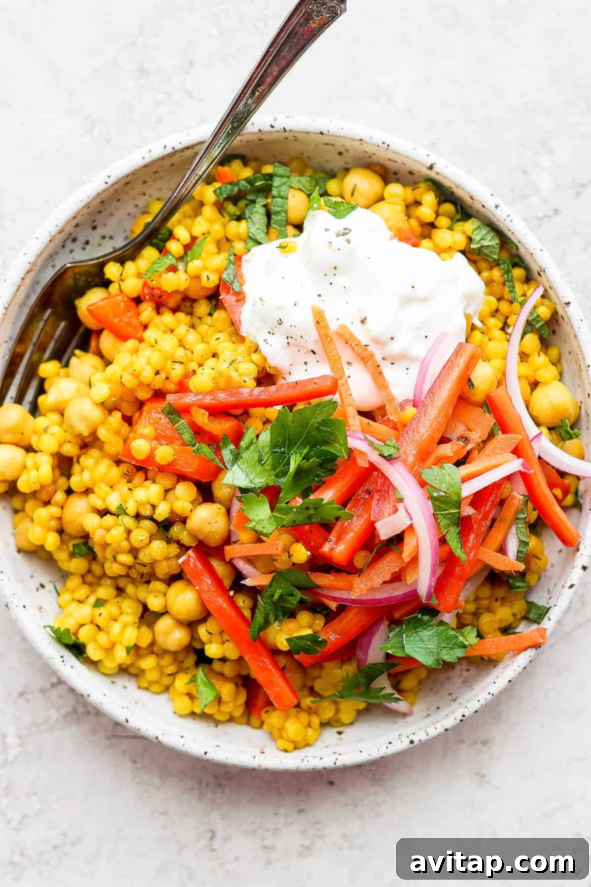 Delicious Lemon Garlic Israeli Couscous topped with creamy whipped feta, fresh herbs, and colorful pickled vegetables.