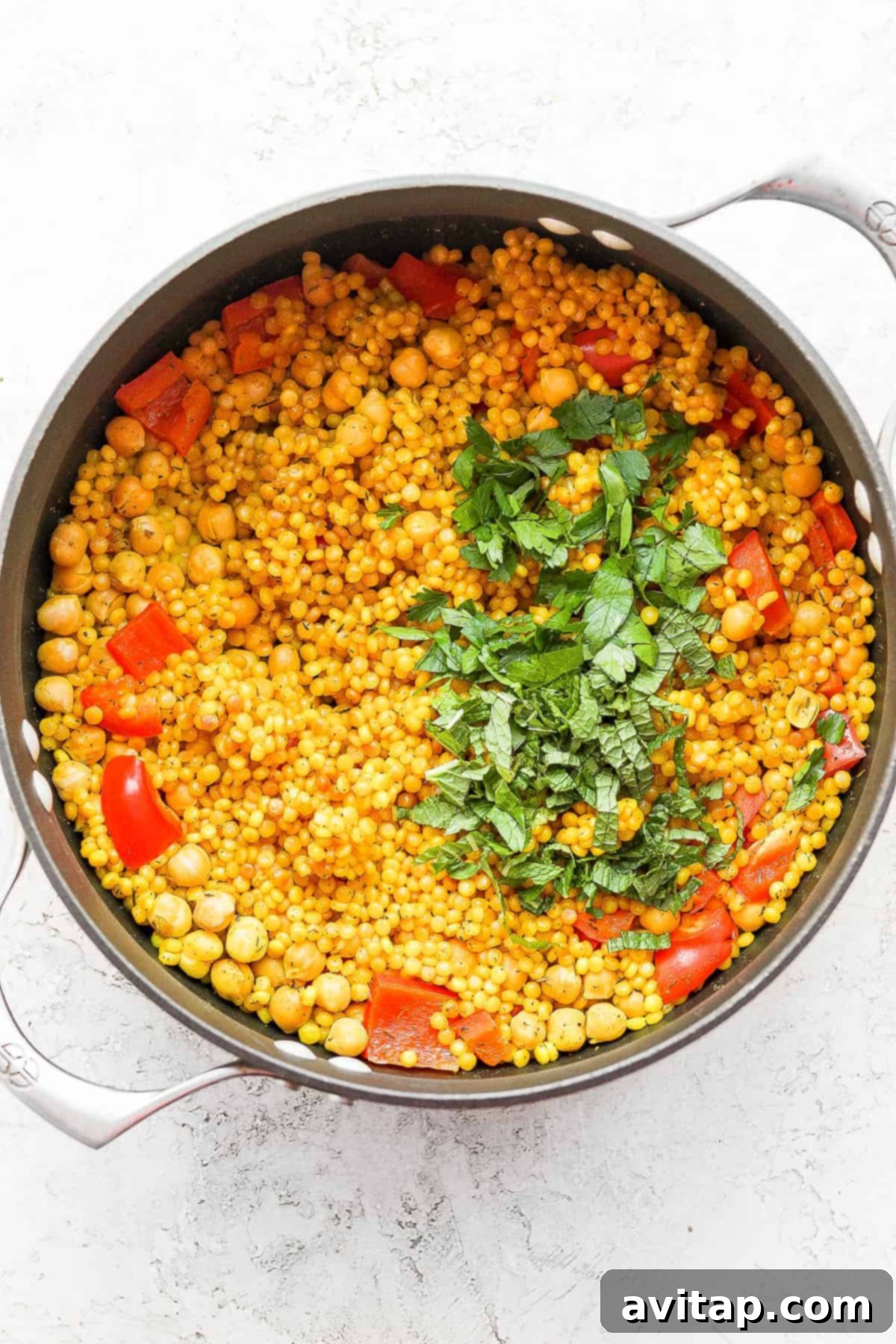 Freshly chopped parsley and mint sprinkled over the cooked Lemon Garlic Israeli Couscous for a vibrant finish.