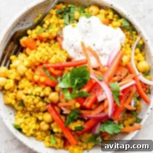 Israeli couscous with beans, garlic, and spices, cooked together in one pot and topped with pickled veggies and whipped feta.