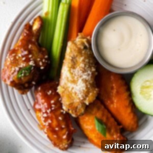 A plate with chicken wings, carrots, celery and dipping sauce.