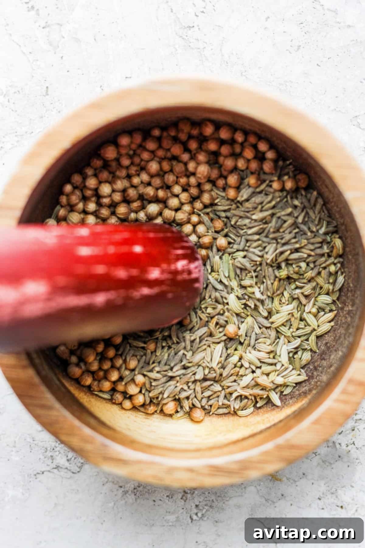 The process of making za'atar: a mortar and pestle filled with whole and crushed aromatic seeds and dried herbs, ready to be blended into the famous seasoning.