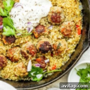 A delicious skillet of one-pot Za'atar Meatballs and Couscous, garnished with fresh herbs, ready to be served.