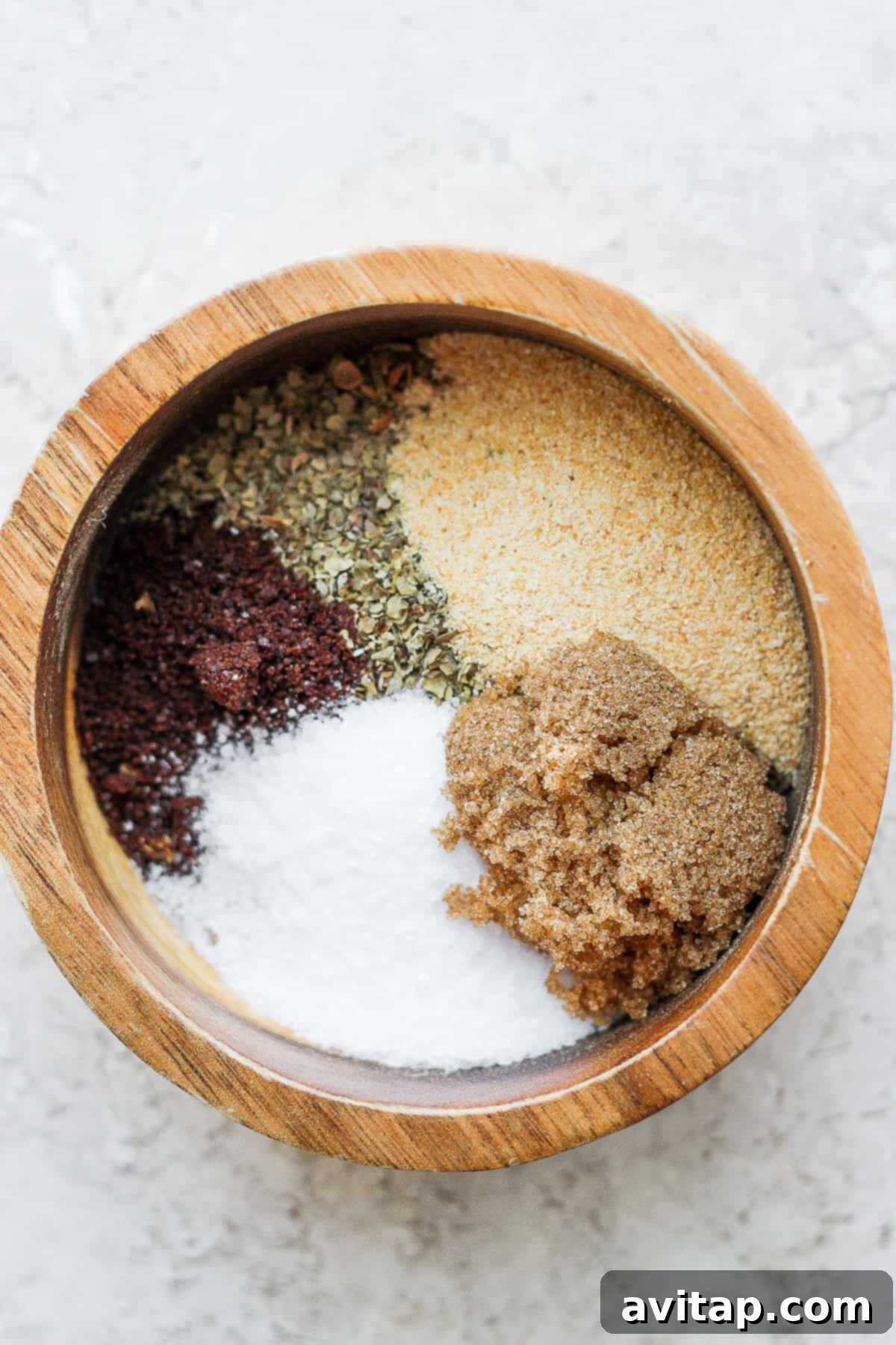Ingredients for Za'atar seasoning laid out in a mortar and pestle, including whole seeds and dried herbs