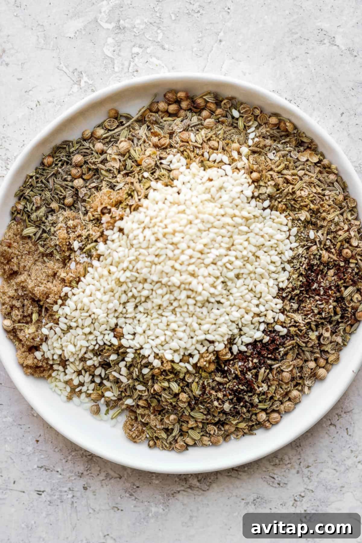 A selection of whole spices for Za'atar seasoning arranged on a plate