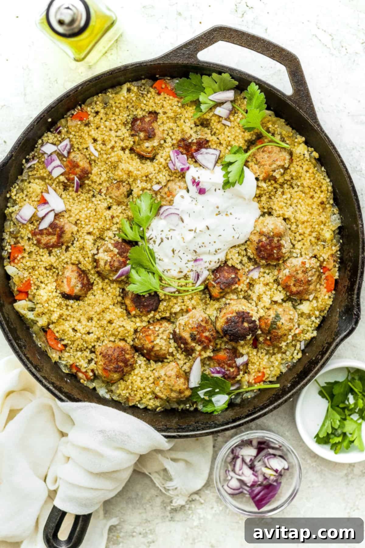 A vibrant cast iron skillet filled with One-Pot Za'atar Meatballs and Quinoa, garnished with fresh herbs.