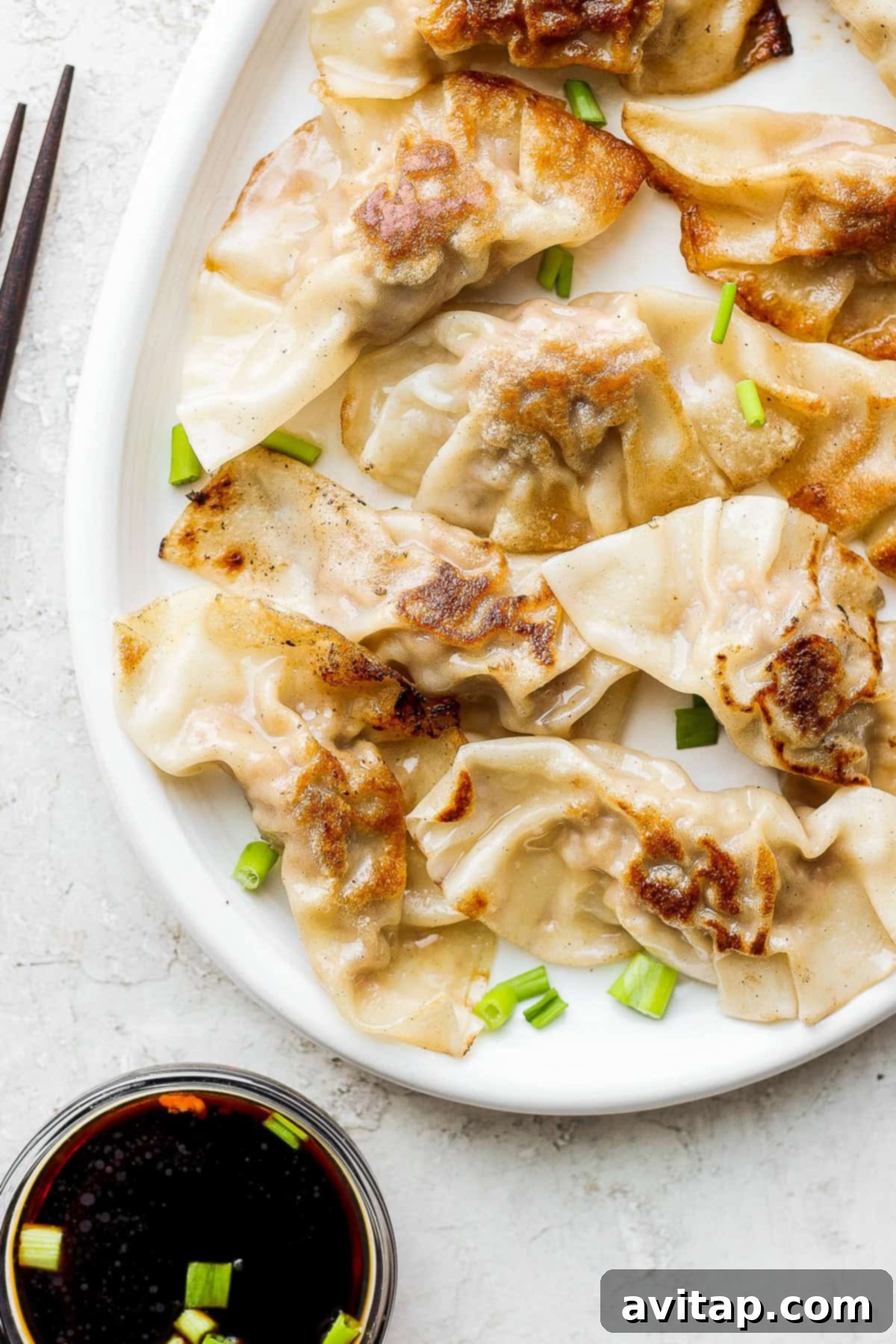 These homemade pork dumplings are packed with savory umami flavors. Make a batch and serve with our amazing sweet dipping sauce that perfectly complements the dumplings. Steaming homemade pork dumplings on a plate, garnished with fresh green onions
