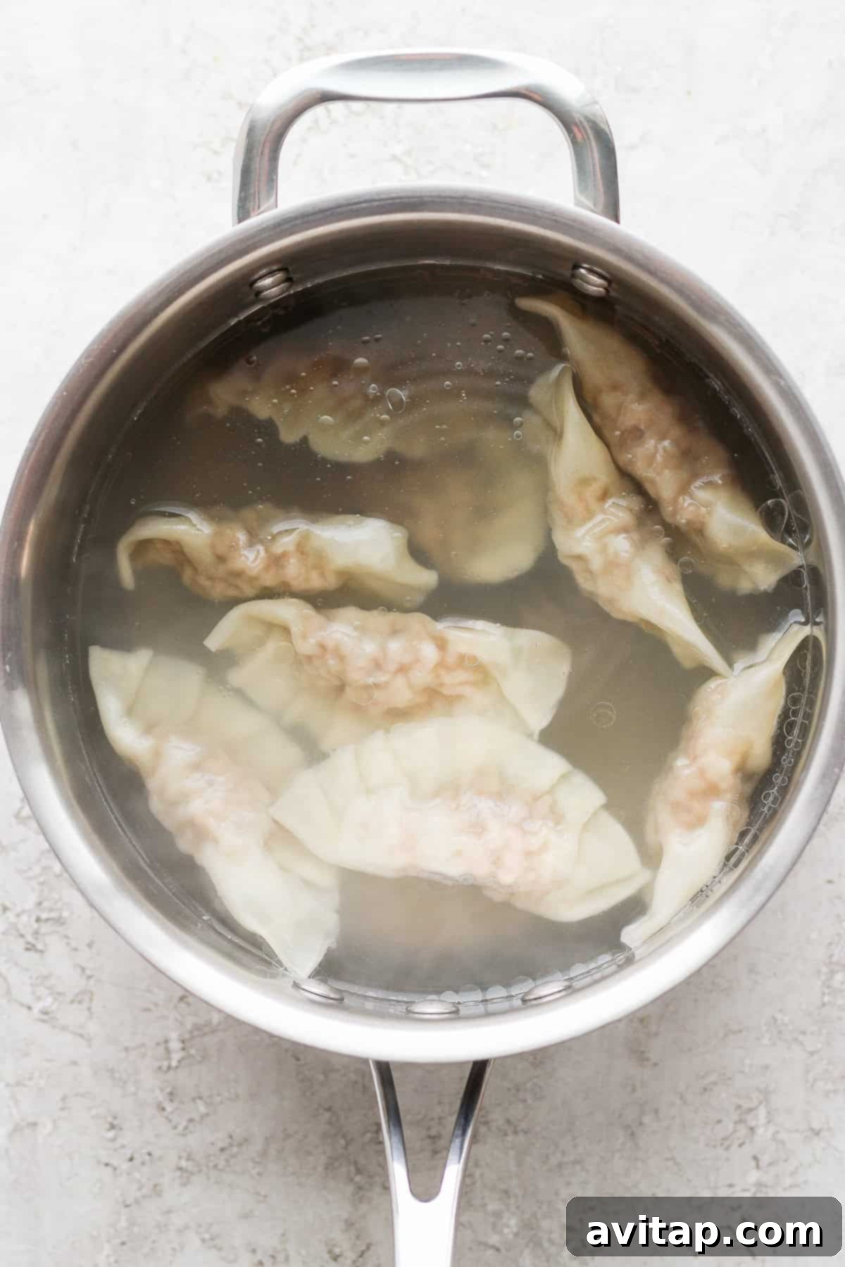 These homemade pork dumplings are packed with savory umami flavors. Make a batch and serve with our amazing sweet dipping sauce that perfectly complements the dumplings. Freshly made pork dumplings simmering in a pot of boiling water