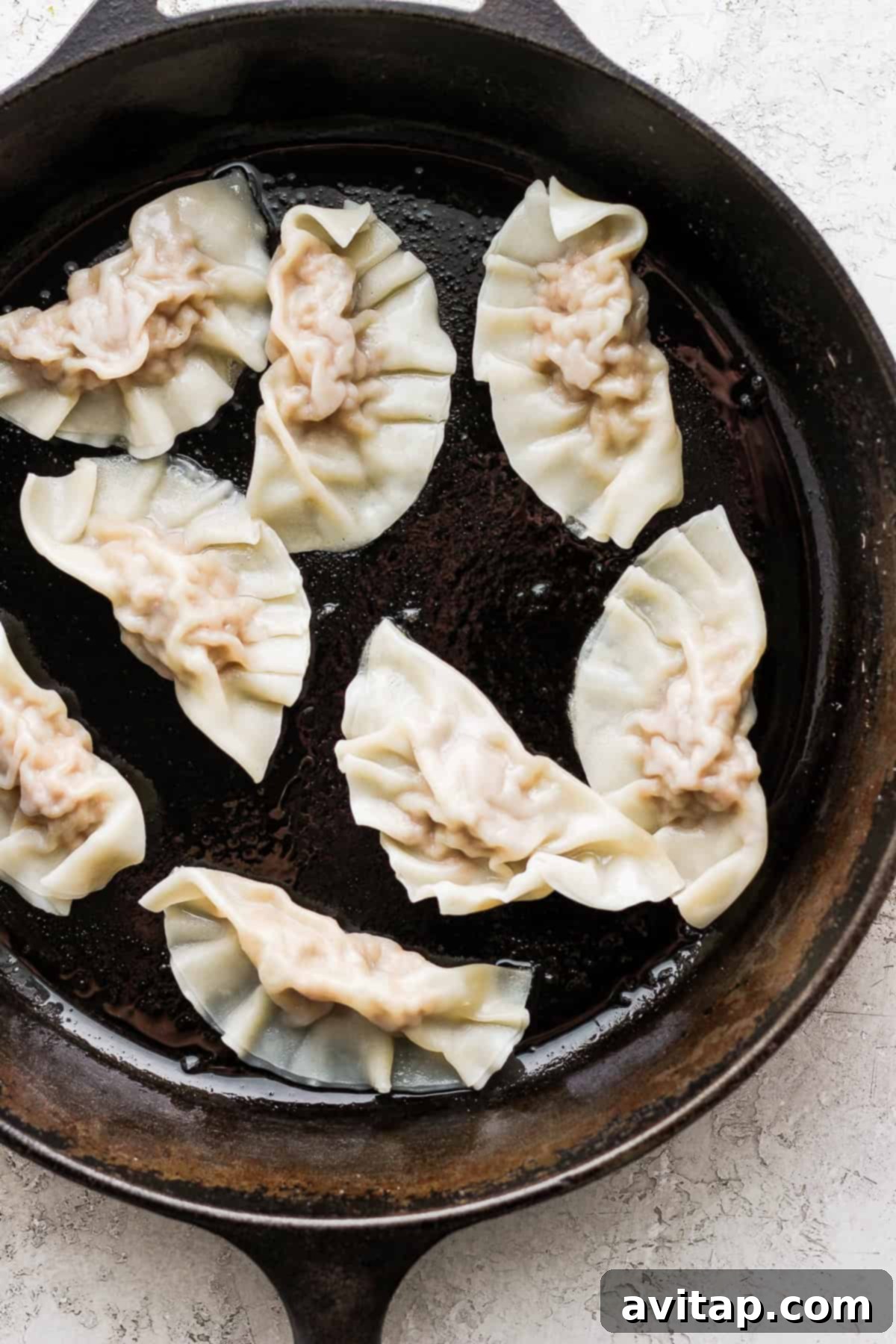 These homemade pork dumplings are packed with savory umami flavors. Make a batch and serve with our amazing sweet dipping sauce that perfectly complements the dumplings. Golden-brown pork dumplings sizzling in a cast iron skillet